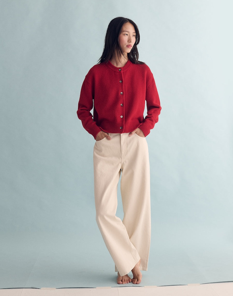 Person wearing a red sweater and beige pants against a light blue background