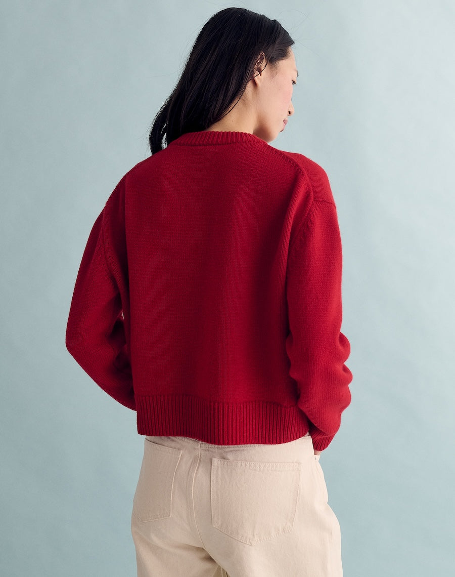 Person wearing a red sweater and beige pants against a light gray background