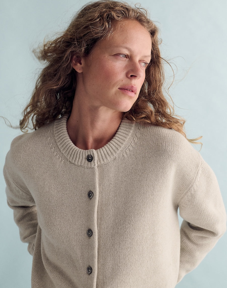 Woman wearing a beige cardigan against a light blue background