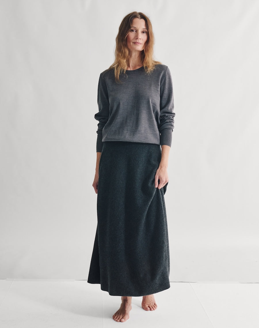 Woman wearing a gray sweater and black skirt on a white background