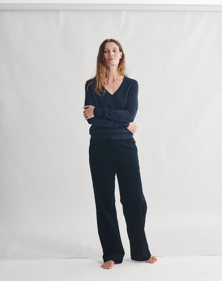 Woman wearing a navy blue outfit standing against a white background