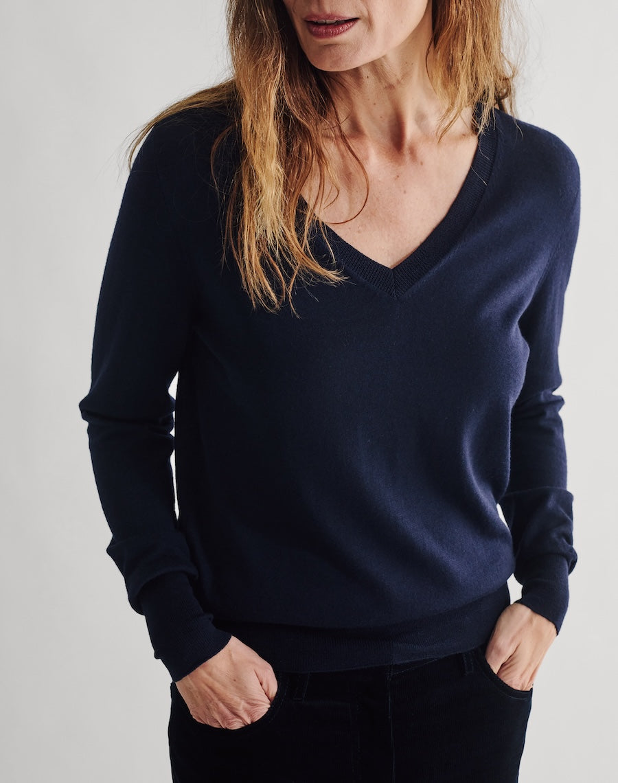 Person wearing a navy blue sweater against a plain background