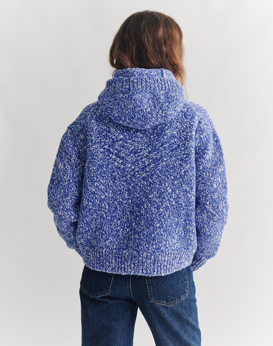 Person wearing a blue knitted hoodie on a white background