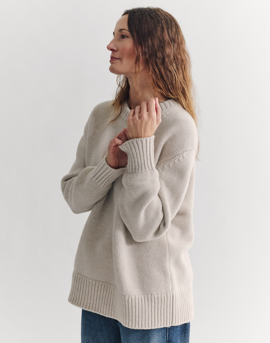 Woman wearing a beige sweater against a white background