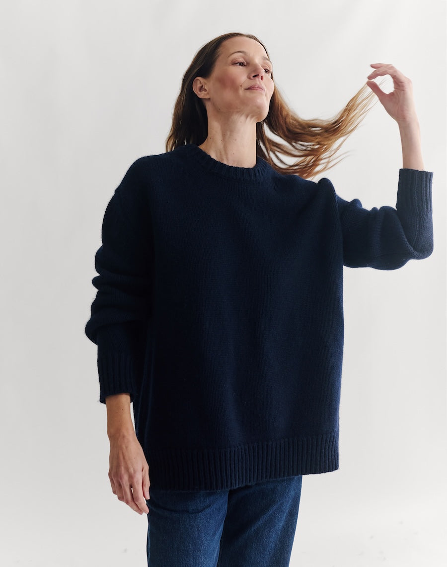 Woman wearing a navy sweater against a white background
