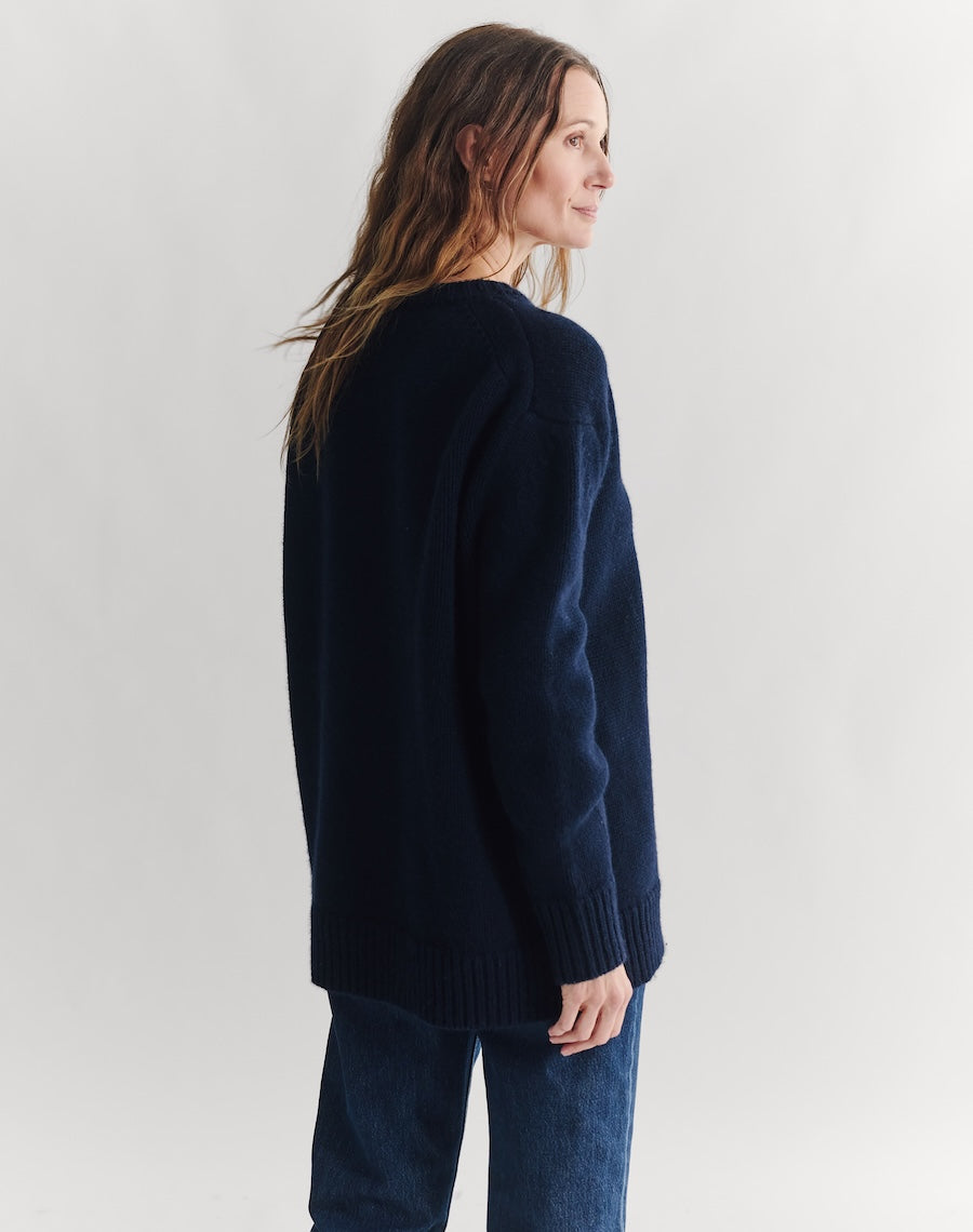 Woman wearing a navy sweater and jeans on a white background