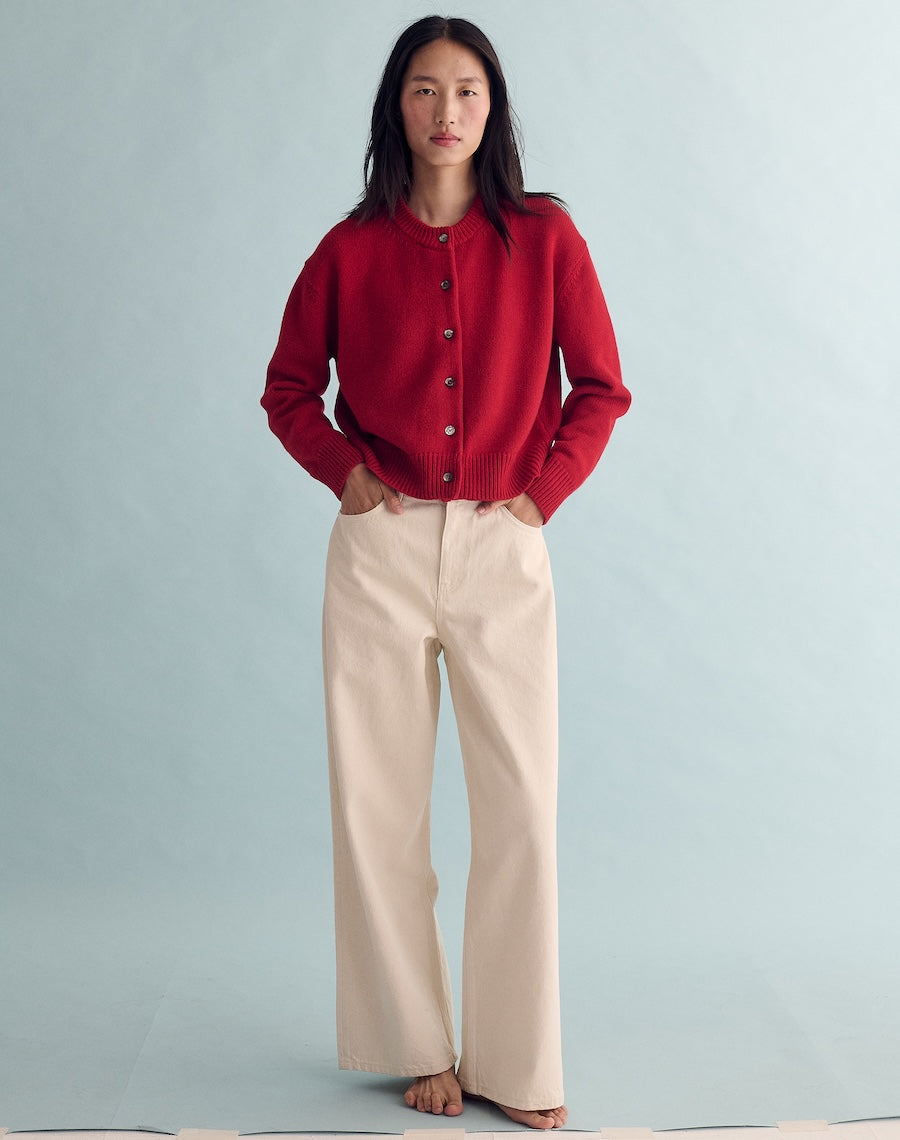 Person wearing a red cardigan and beige pants against a light blue background