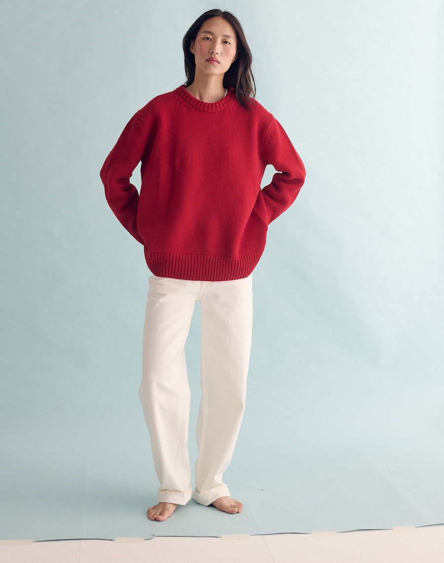 Person wearing a red sweater and white pants against a light blue background