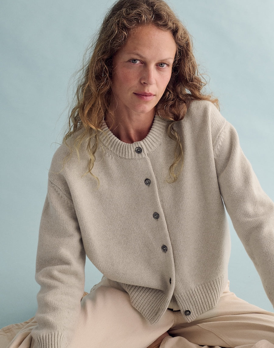 Woman wearing a beige cardigan against a light blue background