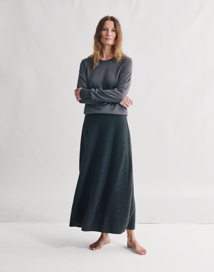Woman wearing a dark gray long-sleeve top and matching long skirt on a white background