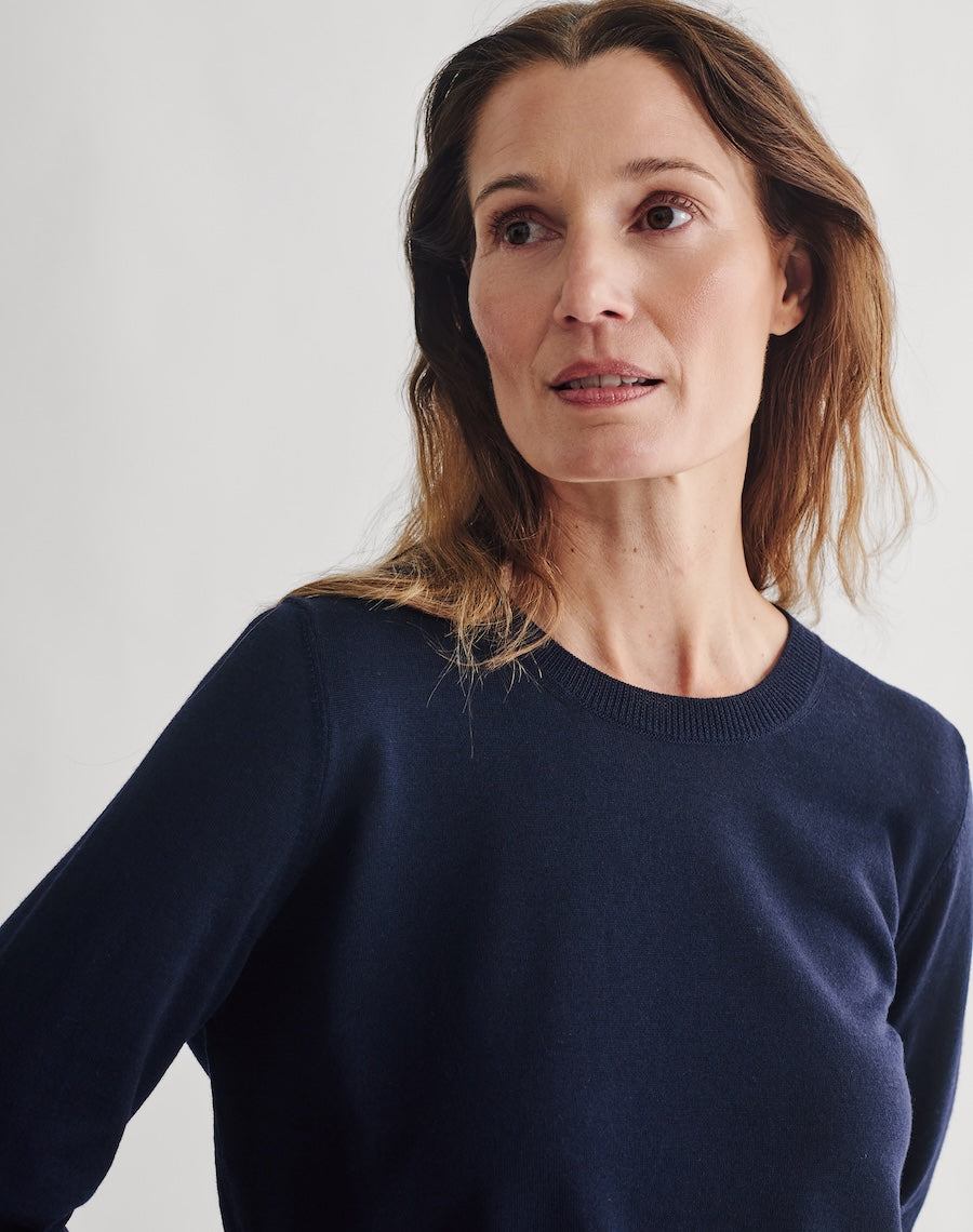 Woman wearing a navy sweater and dark skirt against a plain background