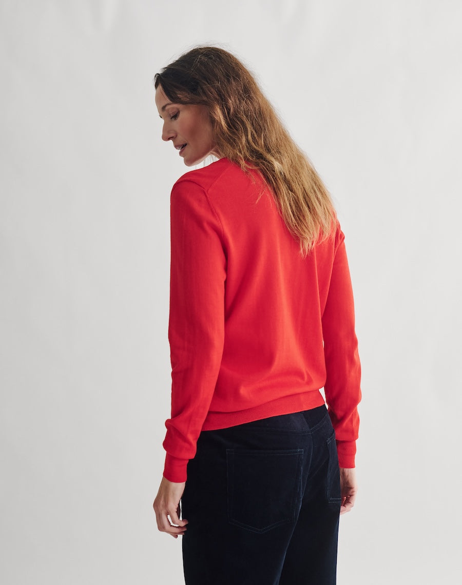 Woman wearing a red sweatshirt and black pants against a white background