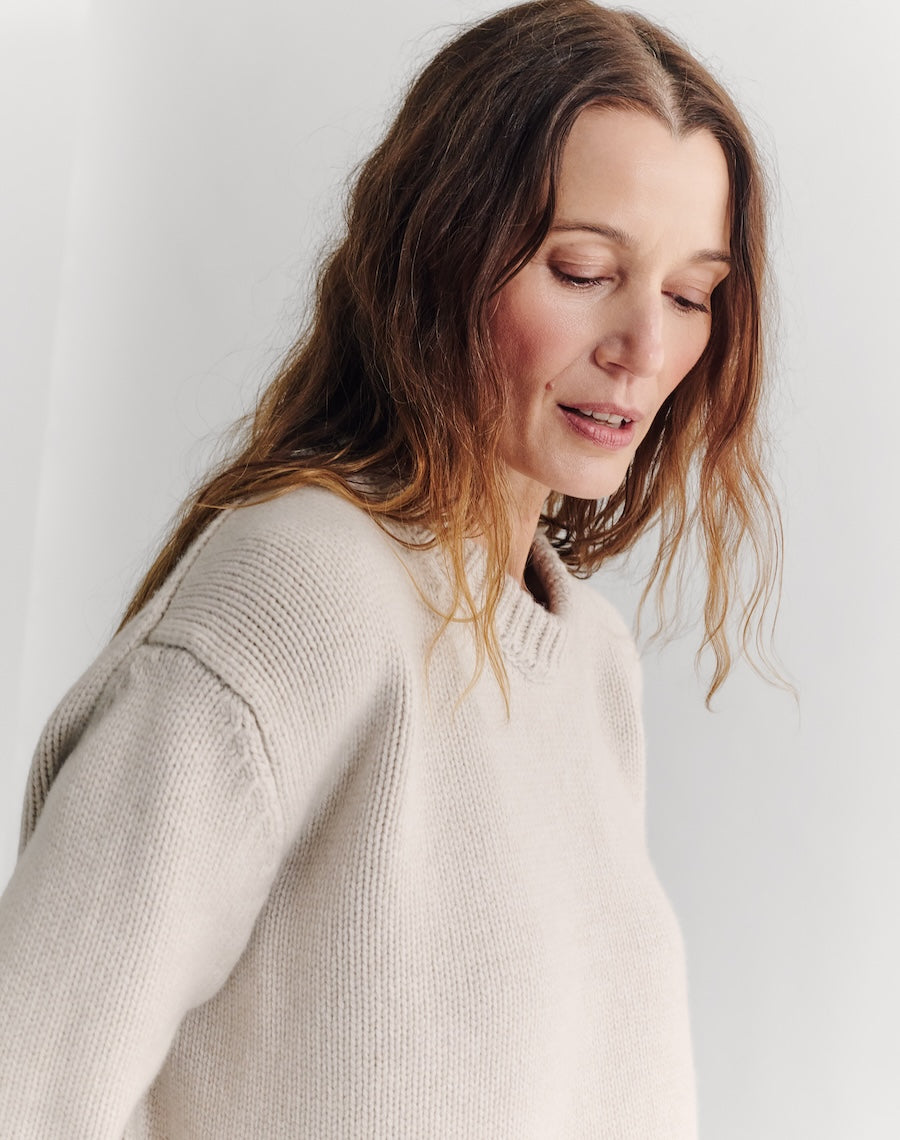 Woman wearing a beige sweater against a plain background
