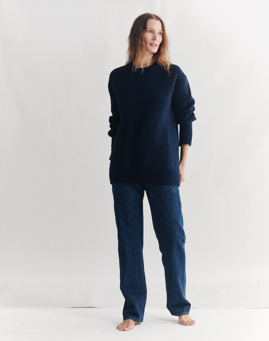 Woman wearing a dark blue sweater and jeans on a white background