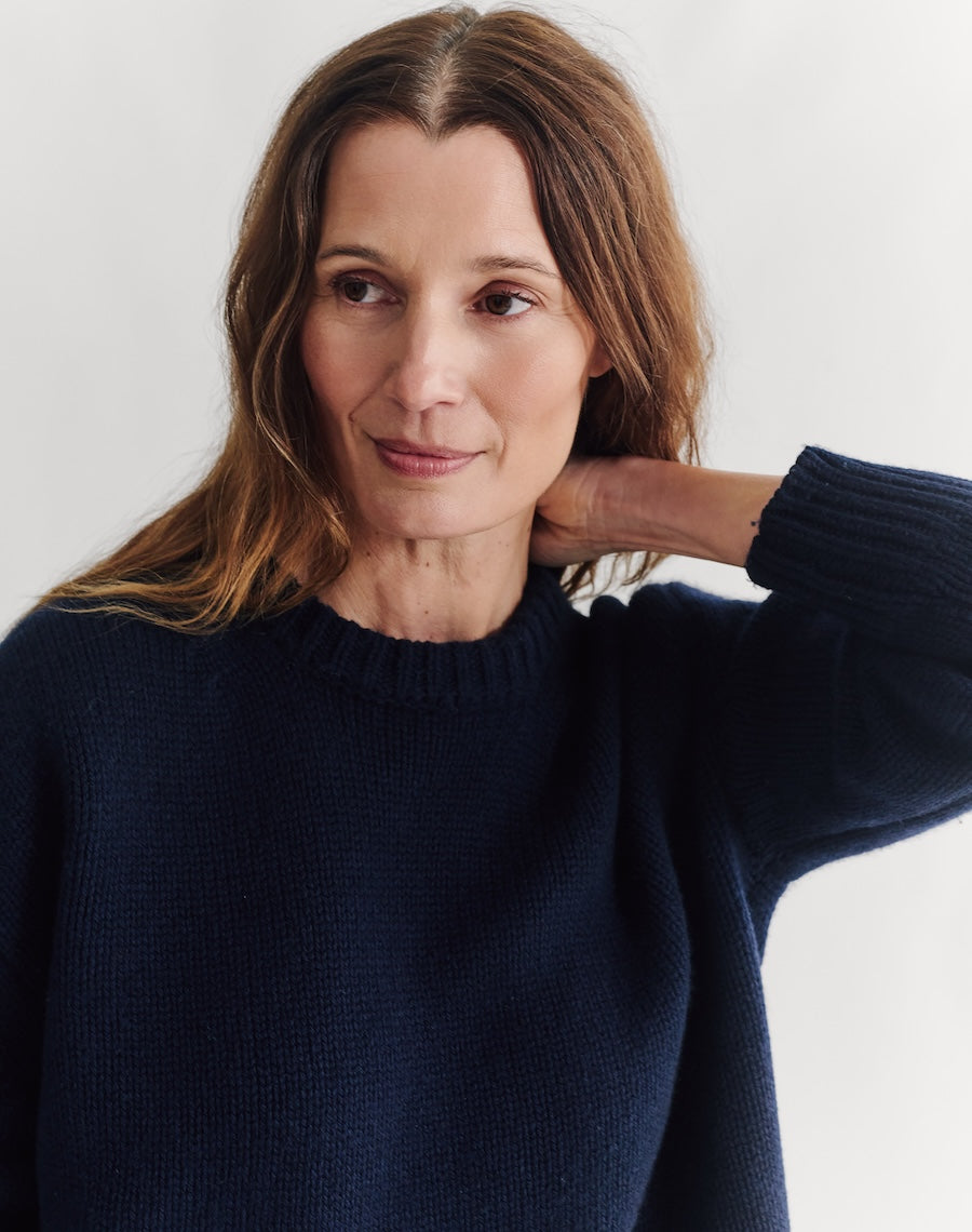 Woman wearing a navy sweater against a white background